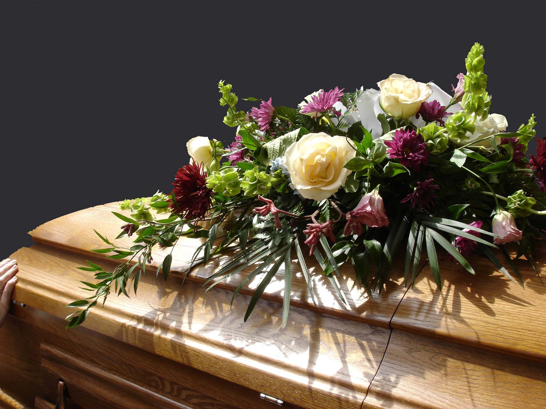 Close-up of flowers laid on top of a wooden casket.