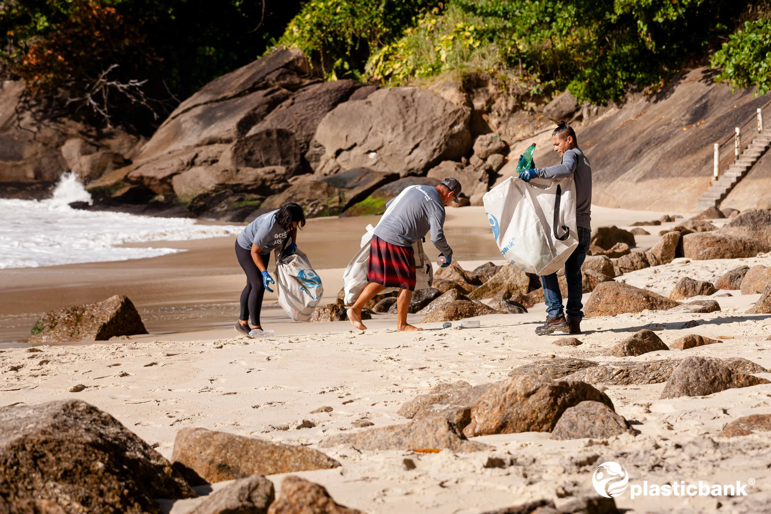 People collecting plastic on a beach as part of a ClimatePartner project